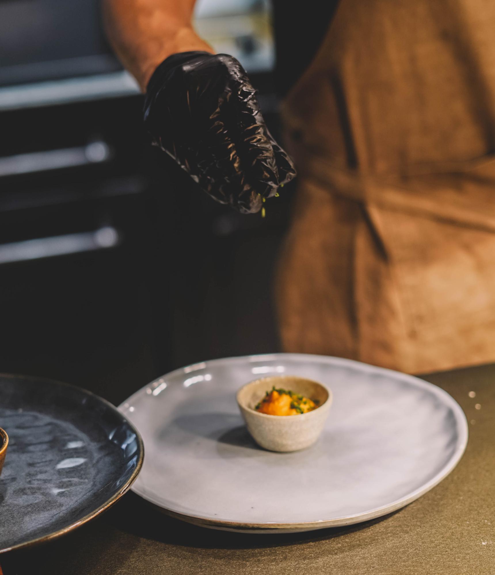 Chef prepares plated dish in workshop